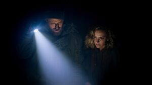 Man and woman in darkness with man shining a torch