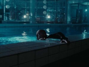Man looking tense as he attempts to lift himself out of a swimming pool