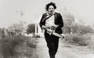 Masked man running and holding a chainsaw